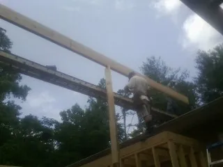 Carpenter setting a ridge beam over a new addition frame — Ice Dam Removal by Roofing Brothers in Anamoose