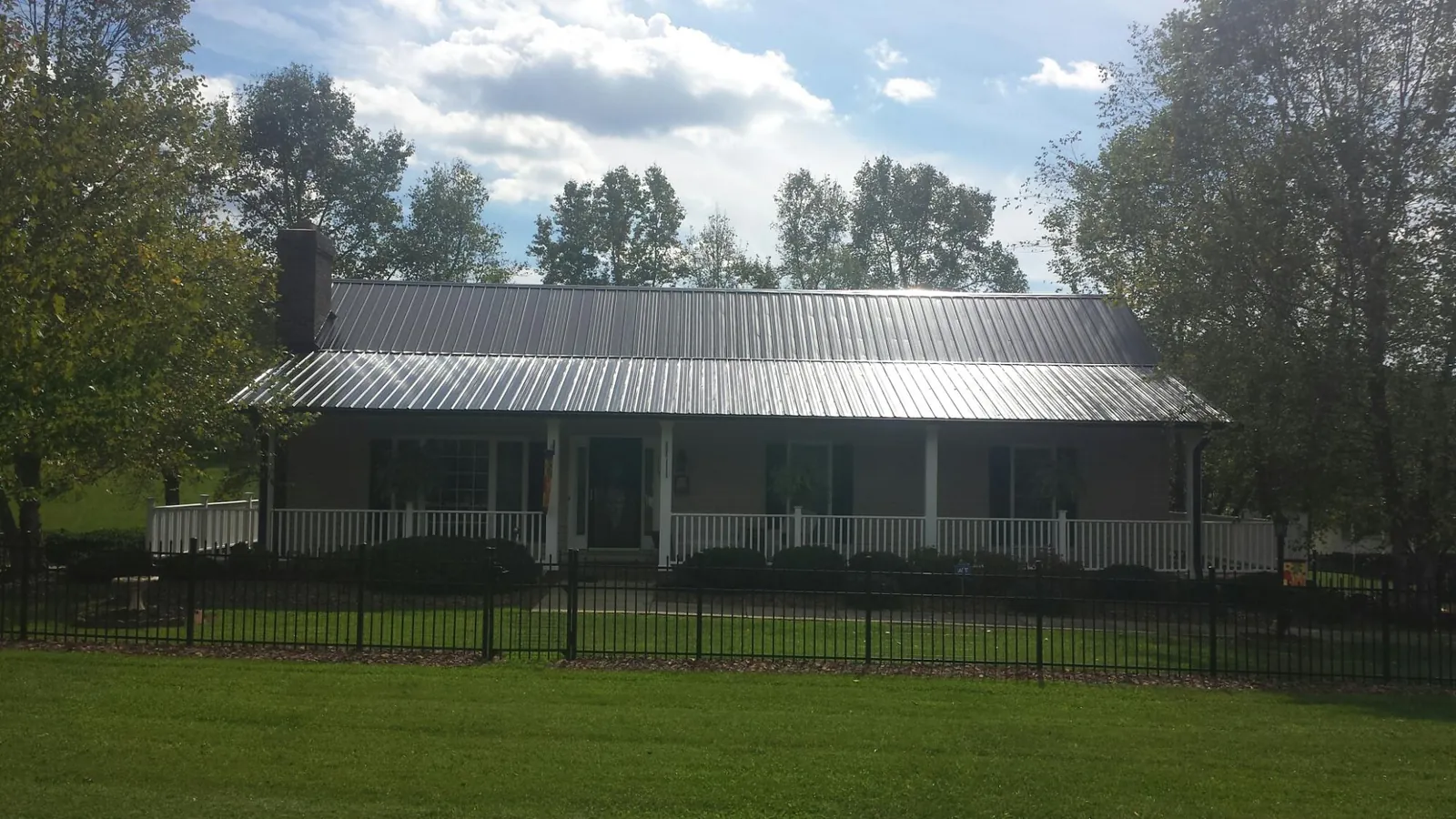 Gray metal roof on a brick ranch with a full width front porch — Gutter Guard Installation work by our crew in Anamoose