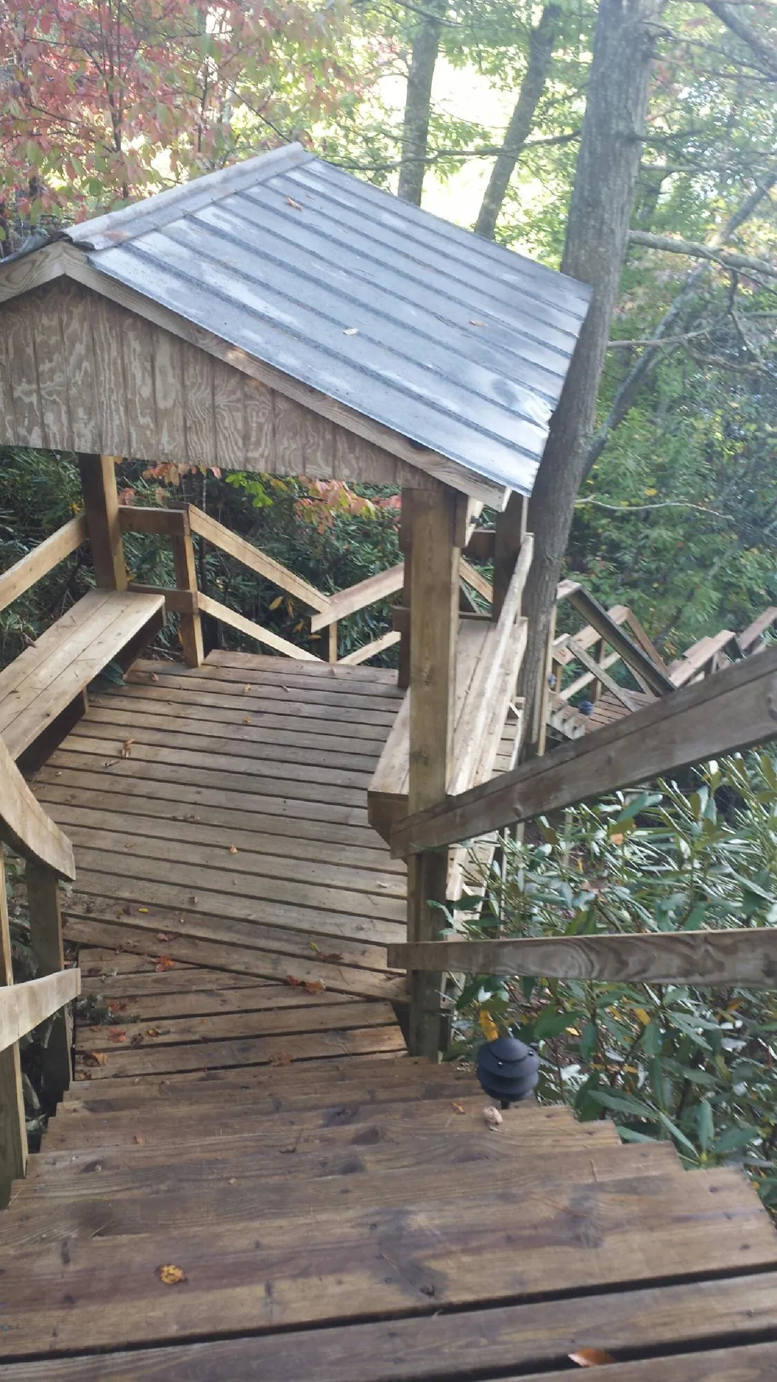 Metal roofed shelter over wooden steps on a wooded walkway — Skylight Repair & Installation work by our crew in Anamoose