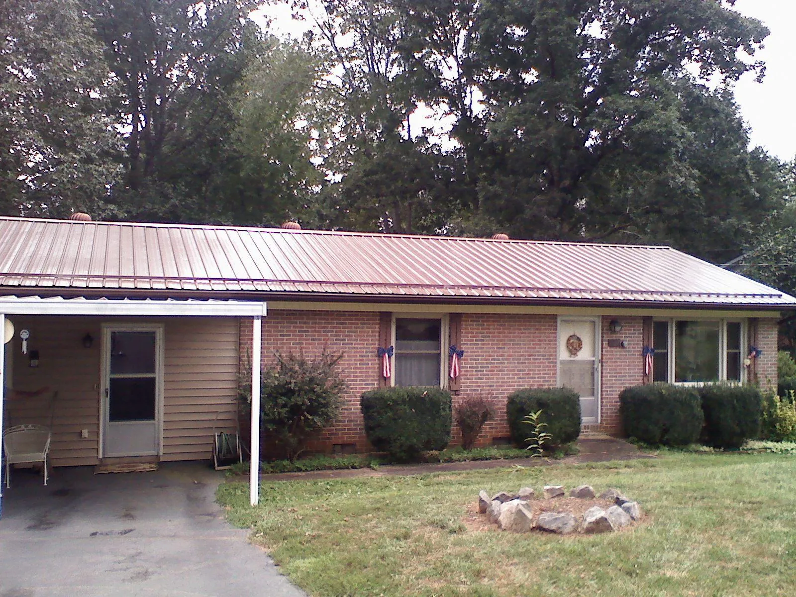 Bronze metal roof and carport on a brick ranch home — Roof Repair work by our crew in Anamoose
