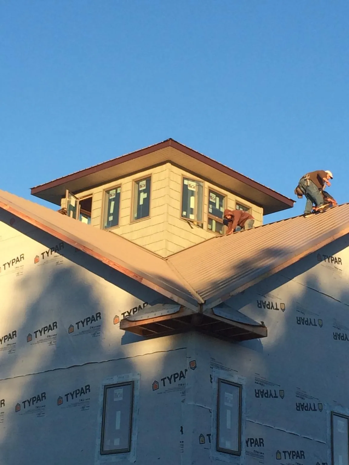 Roofers working around a rooftop cupola on a new metal roof at sunset — Roof Waterproofing in Anamoose by Roofing Brothers